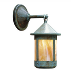 An outdoor wall sconce with a weathered bronze metal body and a warm amber glass shade, shown against a plain white background.