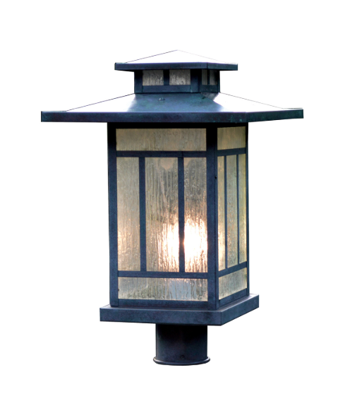 A dark green metal outdoor post cap light with textured glass panels and a warm glowing bulb inside, isolated on a white background.