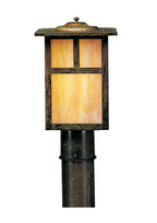 A post cap outdoor light fixture with a dark bronze weathered metal frame and warm yellow-orange illuminated glass panels, mounted on a matching dark post against a plain white background.