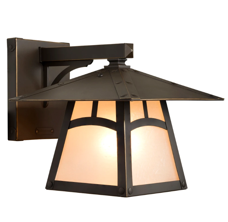 An outdoor wall sconce with a dark bronze metal frame and warm glowing frosted glass panels, shown against a plain white background.