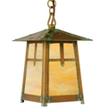 A hanging lantern-style pendant light with a weathered copper-brown metal frame, green patina accents, and warm amber-tinted glass panels, suspended from a chain against a plain white background.