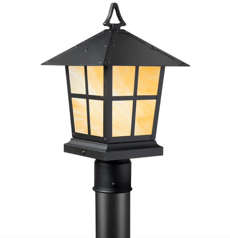 A black metal outdoor post cap light with warm yellow-orange illuminated glass panels, shown on a white background.