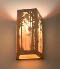 Decorative wall sconce with cut-out design casting a warm glow on a wall.