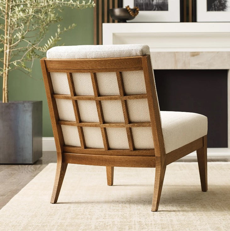 Wooden chair with beige cushion in a room with a fireplace and plant
