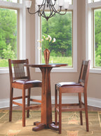 Wooden dining set with two chairs and a small round table in a room with large windows. The Stickley Bar Bistro table.