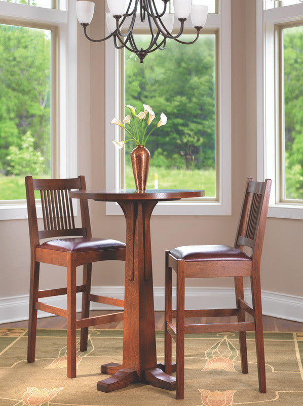 Wooden dining set with two chairs and a small round table in a room with large windows. The Stickley Bar Bistro table.
