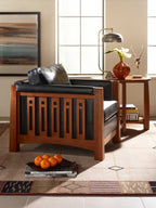 Wooden armchair with black leather seat and backrest in a living room setting.