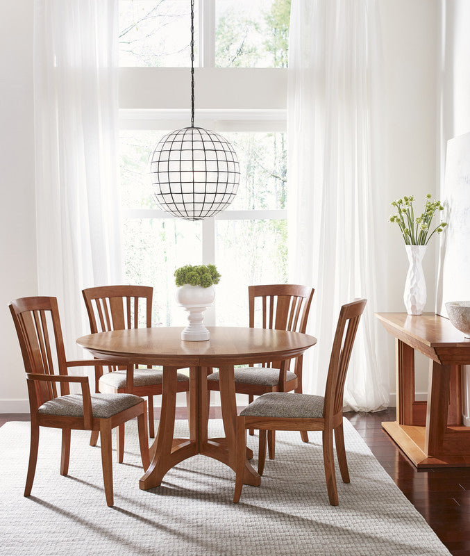 Dining room with wooden table and chairs in a bright room with large windows.