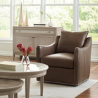 Brown leather armchair in a living room with a round glass coffee table and a cabinet.