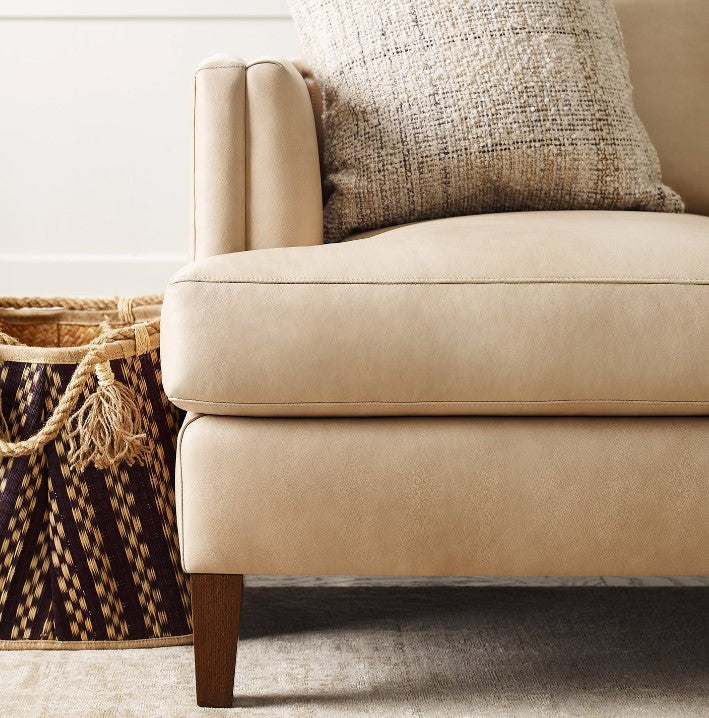 Beige sofa with a textured pillow and woven basket in a room setting
