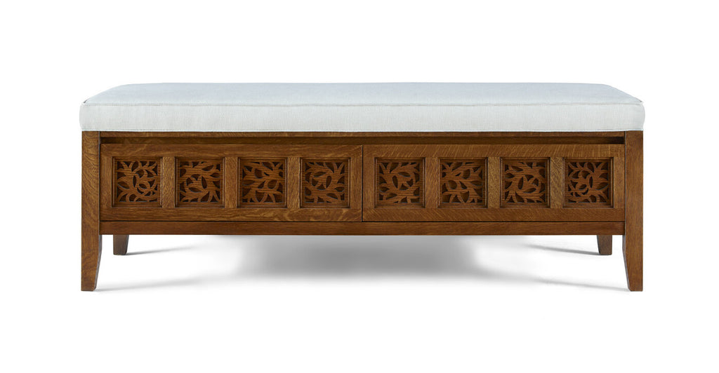 Wooden bench with decorative carvings and a white cushion on a white background