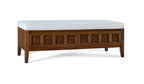 Wooden bench with decorative carvings and a white cushion on a white background