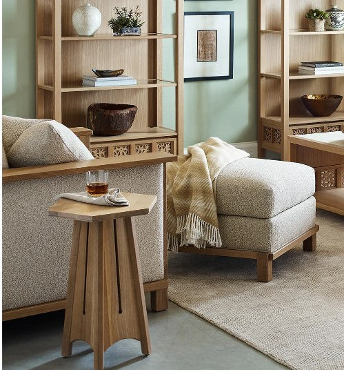 Living room with beige upholstered chairs, wooden side table, and bookshelves.