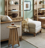 Living room with beige upholstered chairs, wooden side table, and bookshelves.