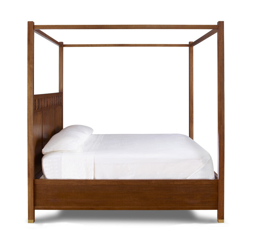 Wooden canopy bed with white bedding on a white background