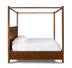 Wooden canopy bed with white bedding on a white background