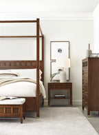 Bedroom with wooden bed, nightstand, and dresser in a well-lit room.
