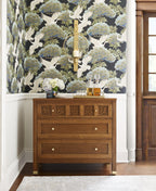 Wooden dresser against a wall with decorative wallpaper featuring birds and foliage.