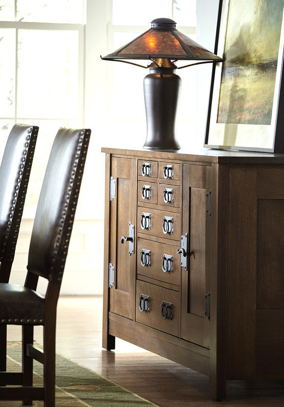 Wooden sideboard with a lamp and chairs in a room setting