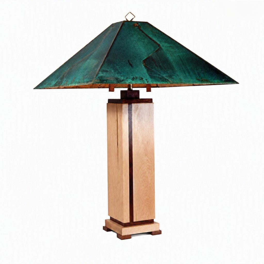 A table lamp with a square wooden pedestal base and a wide, tiered metal shade featuring a distressed green and teal finish with bronze-toned edges, shown against a plain white background.