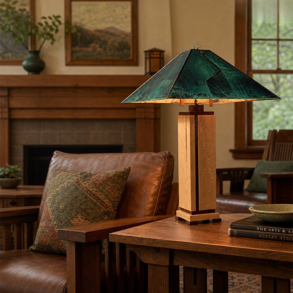 A table lamp with a textured green glass conical shade and a light wood rectangular base sits on a wooden table in a cozy living room setting.