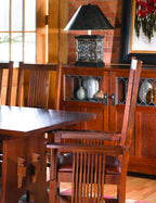 Wooden dining table with chairs and a decorative cabinet in a room with wooden walls.