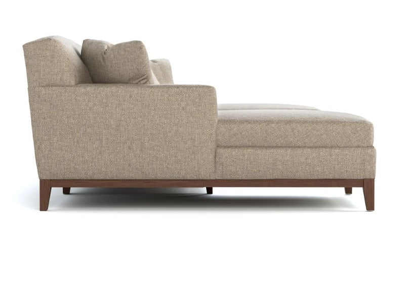 A modern chaise lounge sofa in a textured beige fabric with dark brown wooden legs, shown from a side profile view on a white background.