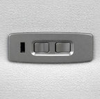 A rectangular brushed metal control panel with two toggle switches and a small vertical slot, mounted on a textured white surface.