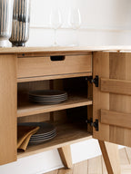 Wooden kitchen cabinet with open door revealing shelves and plates inside.
