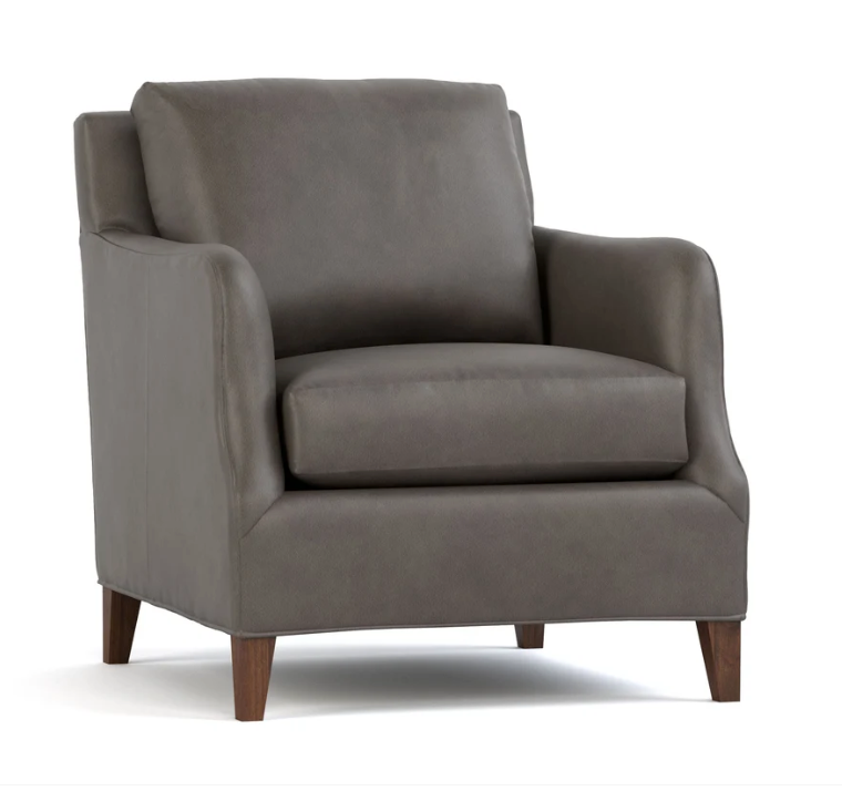 A modern armchair upholstered in dark gray fabric with dark brown wooden legs, shown from a three-quarter angle on a white background.