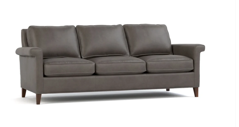 A three-seat sofa upholstered in dark gray fabric with rolled arms, three loose back cushions, three seat cushions, and dark wooden legs, shown on a plain white background.
