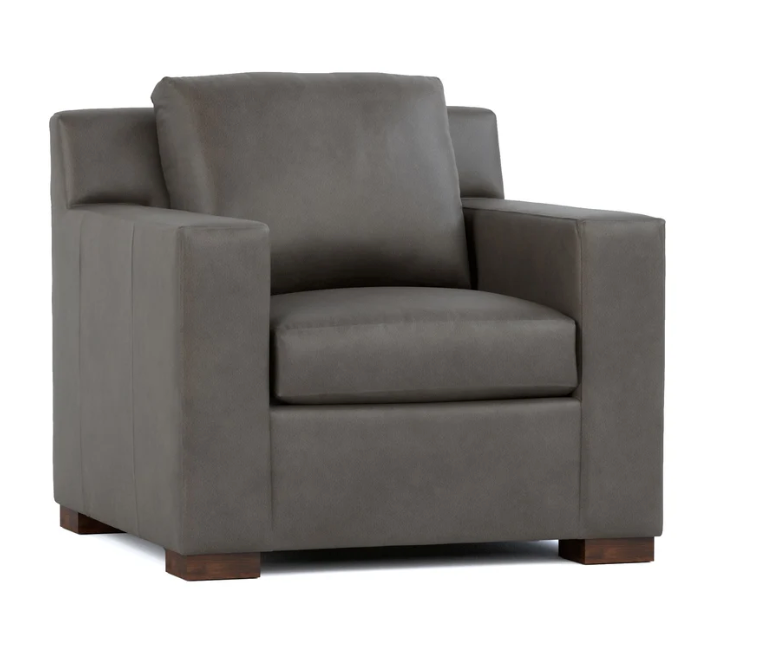 A dark gray upholstered armchair with a square backrest, wide armrests, and dark wooden feet, shown on a plain white background.