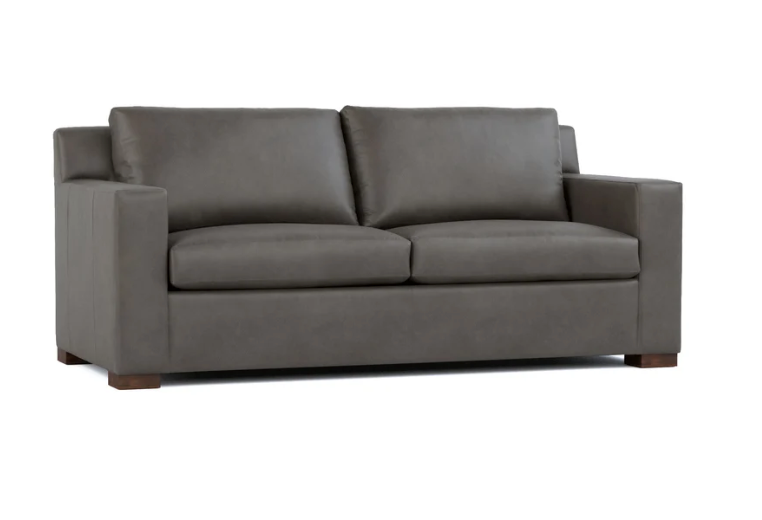 A modern two-seater sofa upholstered in dark gray fabric, featuring square arms, two back cushions, and dark wooden feet, shown against a plain white background.