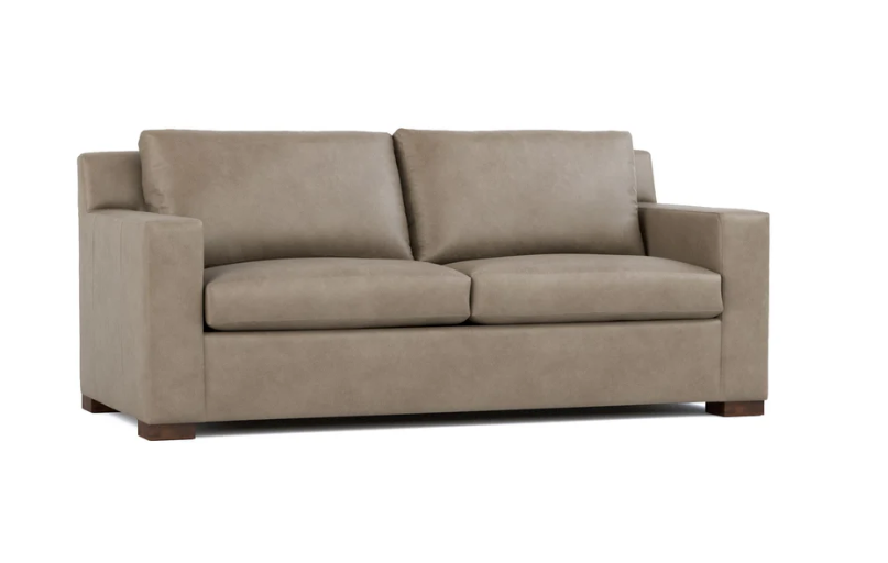 A two-seater loveseat sofa upholstered in a textured taupe fabric, featuring a low profile, square arms, and dark wooden feet, shown against a plain white background.