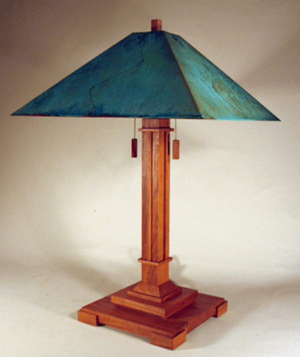 Table lamp with wooden base and teal lampshade on a plain background