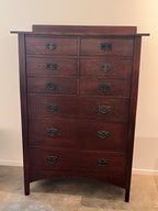 Wooden dresser with multiple drawers against a plain wall.