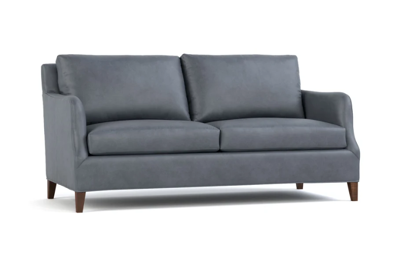 A modern two-seater loveseat sofa upholstered in dark gray fabric, featuring dark brown wooden legs, shown against a plain white background.